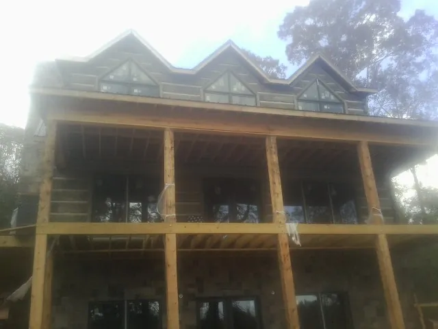 Dormers and porch framing on a large log home under construction — Roof Coating work by our crew in Johnsonville