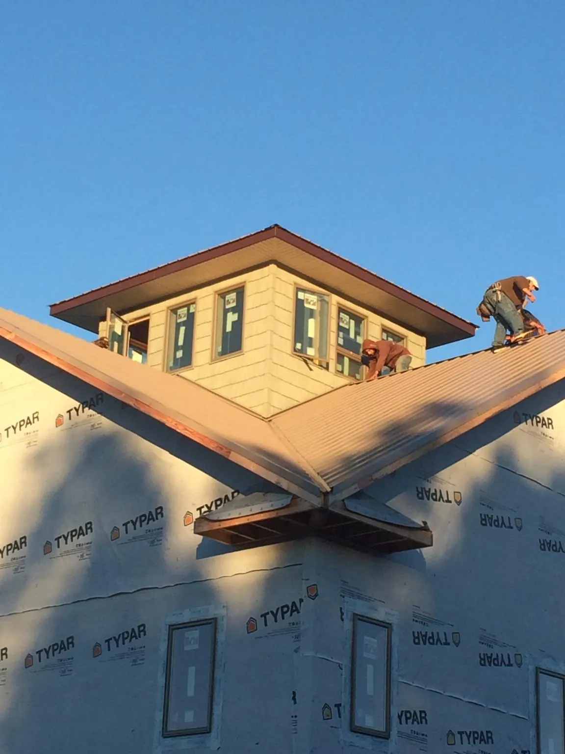 Roofers working around a rooftop cupola on a new metal roof at sunset — Roof Waterproofing in Johnsonville by Roofing Brothers